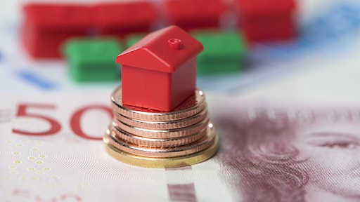 A monopoly house on top of Swedish coins.