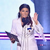 A woman in a white outfit accepting a prize.