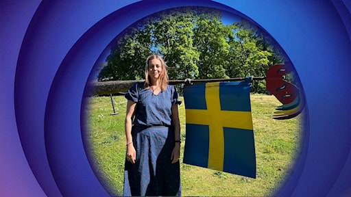 A woman in a summer dress stood by a pole with a Sweden flag.